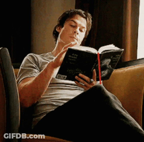 A Man Is Sitting On A Couch Reading A Book With A Sticker That Says ' A ' On It GIF