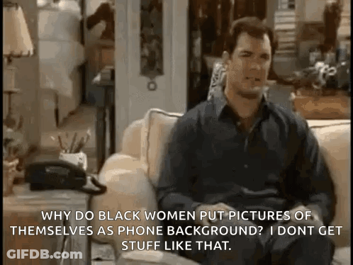 A Man Is Sitting On A Couch Talking To A Woman While Holding A Telephone . GIF