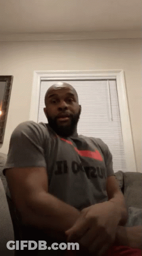 A Man Is Sitting On A Couch Wearing A Nike Shirt That Says Just Do It GIF