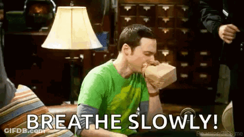 A Man Is Sitting On A Couch With A Bag In His Mouth And The Words `` Breathe Slowly '' . GIF