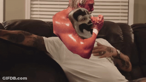 A Man Is Sitting On A Couch With A Red Mask On His Arm GIF