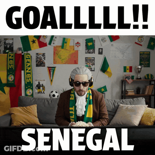 A Man Is Sitting On A Couch With A Scarf Around His Neck That Says Senegal GIF