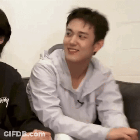 A Man Is Sitting On A Couch With His Arms Around Another Man . GIF