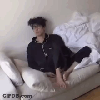 A Man Is Sitting On A Couch With His Feet Up And A Messy Haircut . GIF