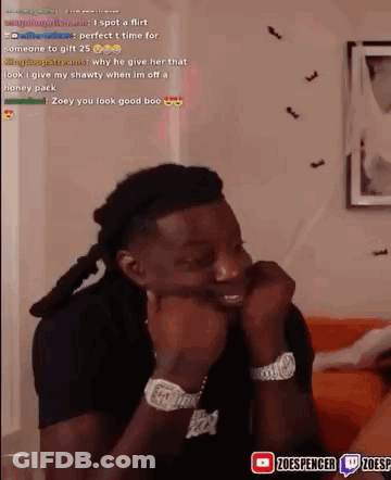 A Man Is Sitting On A Couch With His Hands On His Face And Looking At The Camera . GIF