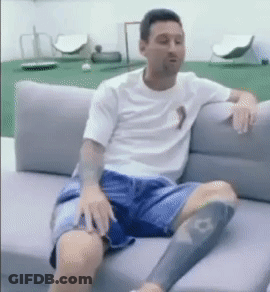 A Man Is Sitting On A Couch With His Legs Crossed GIF