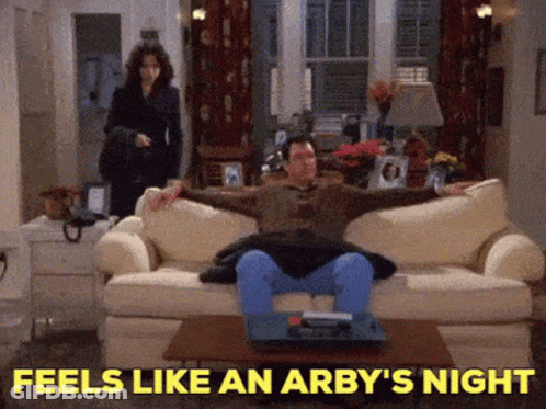 A Man Is Sitting On A Couch With The Words Feels Like An Arby 'S Night Behind Him GIF