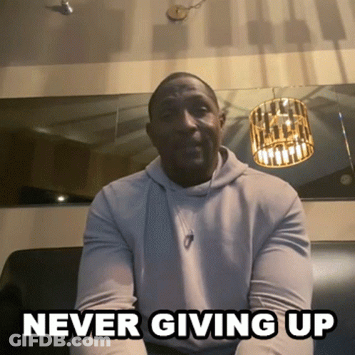 A Man Is Sitting On A Couch With The Words " Never Giving Up " Written Below Him GIF