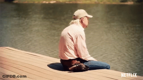 A Man Is Sitting On A Dock With A Netflix Logo Behind Him GIF