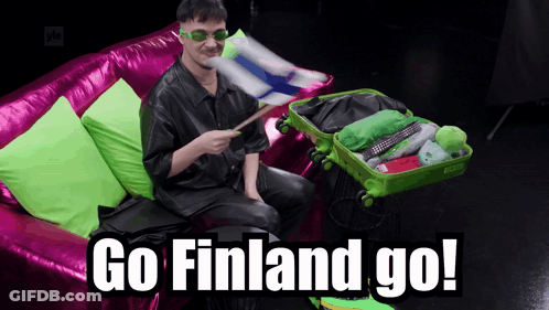 A Man Is Sitting On A Pink Couch With A Green Suitcase That Says " Go Finland Go " GIF