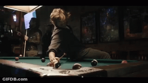 A Man Is Sitting On A Pool Table With A Pool Cue GIF