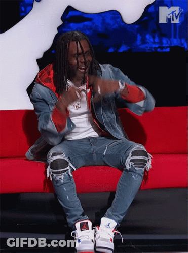 A Man Is Sitting On A Red Couch In Front Of A Mtv Sign GIF