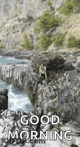 A Man Is Sitting On A Rock Overlooking The Ocean With A Good Morning Message . GIF