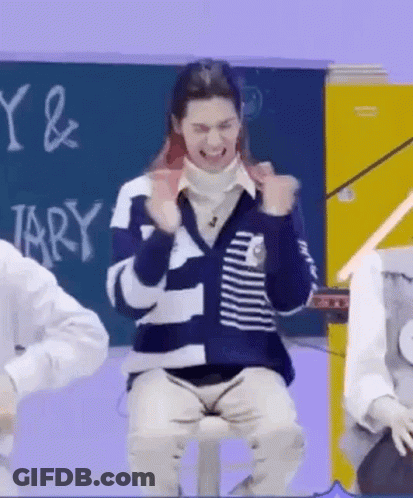 A Man Is Sitting On A Stool In Front Of A Blackboard In A Classroom And Making A Funny Face . GIF