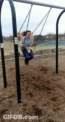A Man Is Sitting On A Swing With A Warning Sign On It GIF