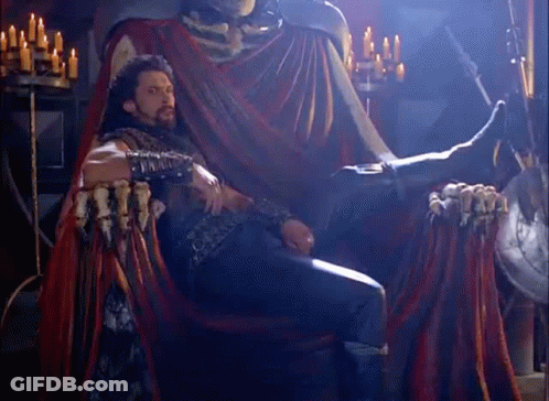 Man Sitting On Throne In Front Of Skeleton Statue GIF