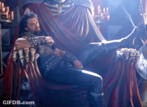 Man Sitting On Throne With Statue Behind GIF