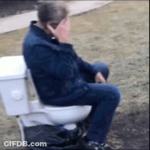 A Man Is Sitting On A Toilet Talking On His Cell Phone . GIF