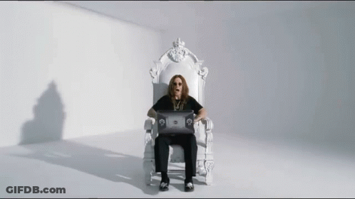 A Man Is Sitting On A White Throne Using A Laptop Computer . GIF