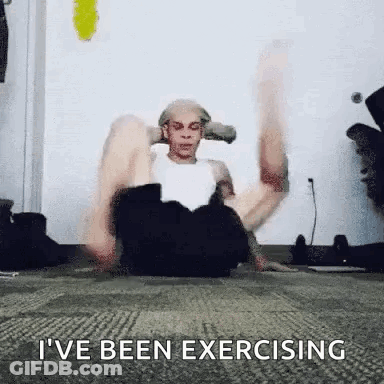 A Man Is Sitting On The Floor Doing Exercises With His Legs Up . GIF