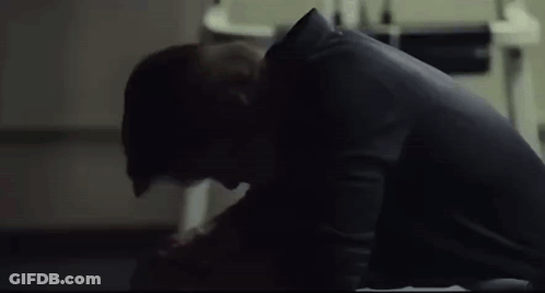 A Man Is Sitting On The Floor In A Dark Room Looking Down . GIF