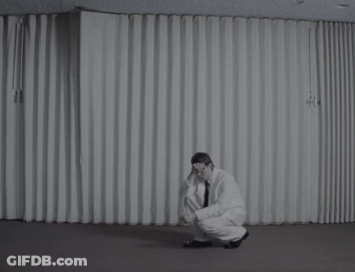 A Man Is Sitting On The Floor With His Head Down GIF