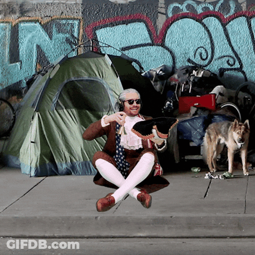 A Man Is Sitting On The Sidewalk In Front Of A Tent With The Word N On It GIF