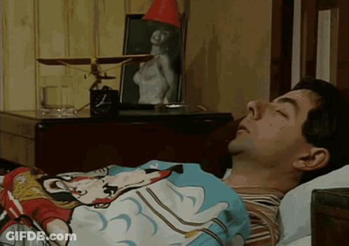 A Man Is Sleeping In A Bed With A Mickey Mouse Blanket On GIF