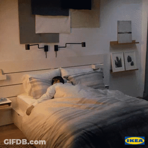 A Man Is Sleeping In A Bed With An Ikea Logo In The Background GIF