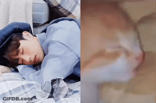 A Man Is Sleeping On A Bed Next To A Picture Of A Cat GIF