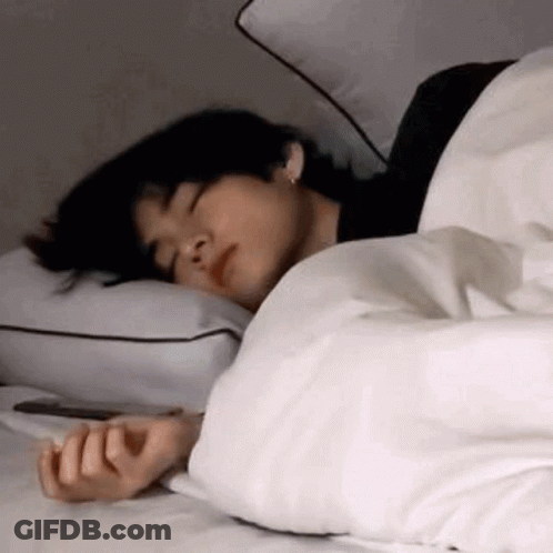A Man Is Sleeping On A Bed With A White Blanket And Pillows . GIF