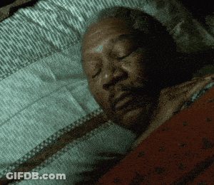 A Man Is Sleeping With His Eyes Closed In A Dark Room GIF