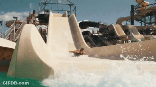 A Man Is Sliding Down A Water Slide In A Water Park GIF