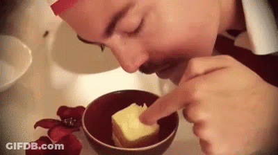 A Man Is Smelling A Piece Of Butter In A Bowl . GIF