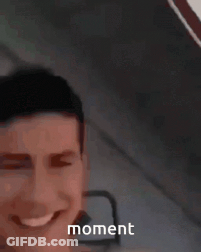 A Man Is Smiling And Holding A Yellow Object In Front Of Him With The Word Moment Visible GIF