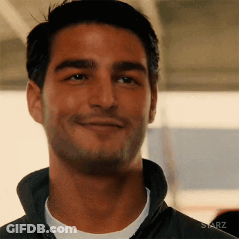 A Man Is Smiling And Looking At The Camera While Wearing A Black Jacket . GIF