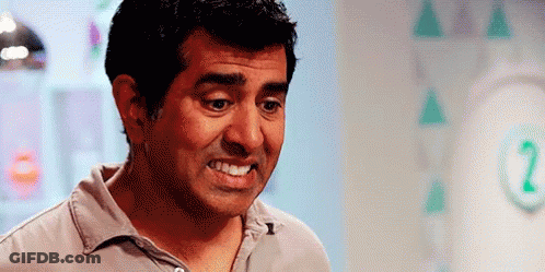 A Man Is Smiling And Making A Funny Face In Front Of A Wall With Triangles On It . GIF
