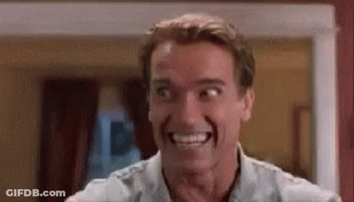 A Man Is Smiling And Making A Funny Face While Standing In A Room . GIF