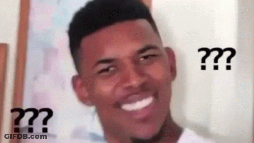 A Man Is Smiling And Making A Funny Face With Three Question Marks . GIF