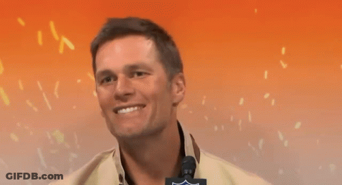 A Man Is Smiling And Pointing At The Camera With A Nfl Logo On His Jacket GIF
