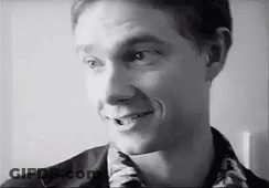 A Man Is Smiling In A Black And White Photo . GIF