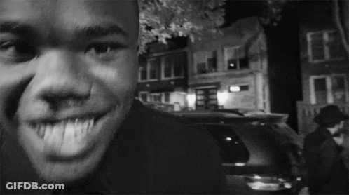 A Man Is Smiling In A Black And White Photo With A Car In The Background GIF