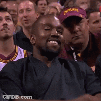 A Man Is Smiling In A Crowd Of People While Wearing A Purple Hat . GIF