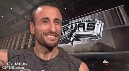 A Man Is Smiling In Front Of A Banner For The San Antonio Spurs GIF