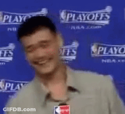 A Man Is Smiling In Front Of A Blue Wall That Says Playoffs . GIF