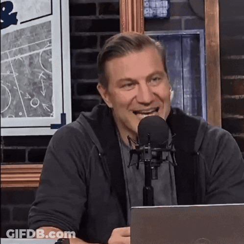 A Man Is Smiling In Front Of A Microphone While Sitting In Front Of A Dell Laptop GIF