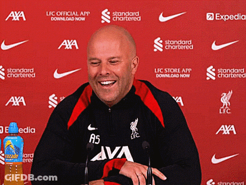 A Man Is Smiling In Front Of A Red Background That Says ' Standard Chartered ' GIF