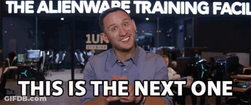 A Man Is Smiling In Front Of A Sign That Says " The Alienware Training Facil " GIF