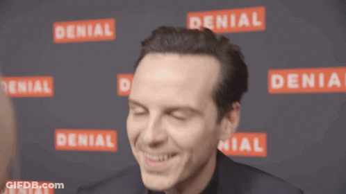 A Man Is Smiling In Front Of A Wall That Has Denial Written On It GIF