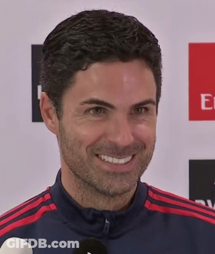 A Man Is Smiling In Front Of An Emirates Logo GIF
